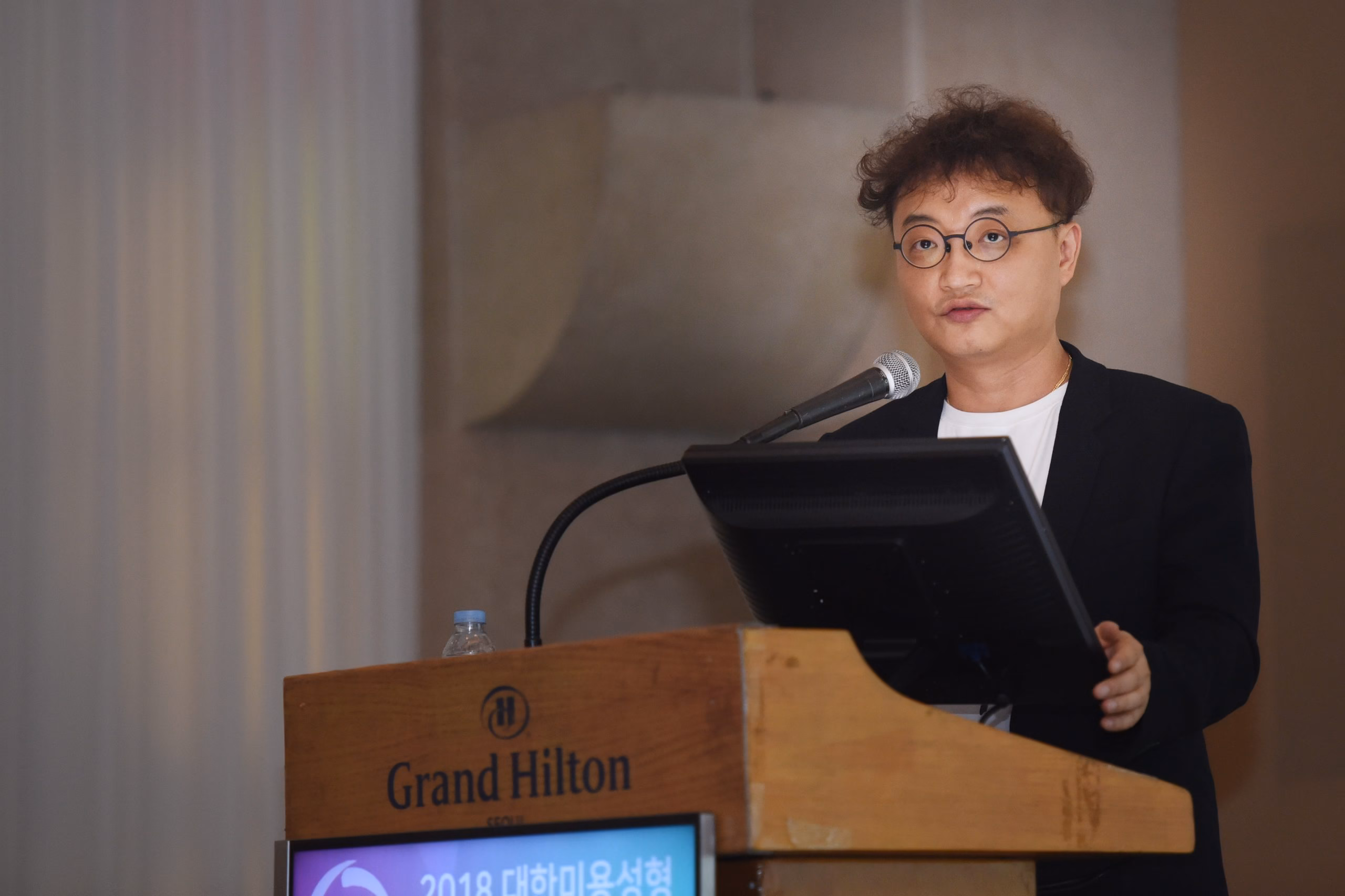 Dr Hyoung Moon Kim lecturing at a conference podium